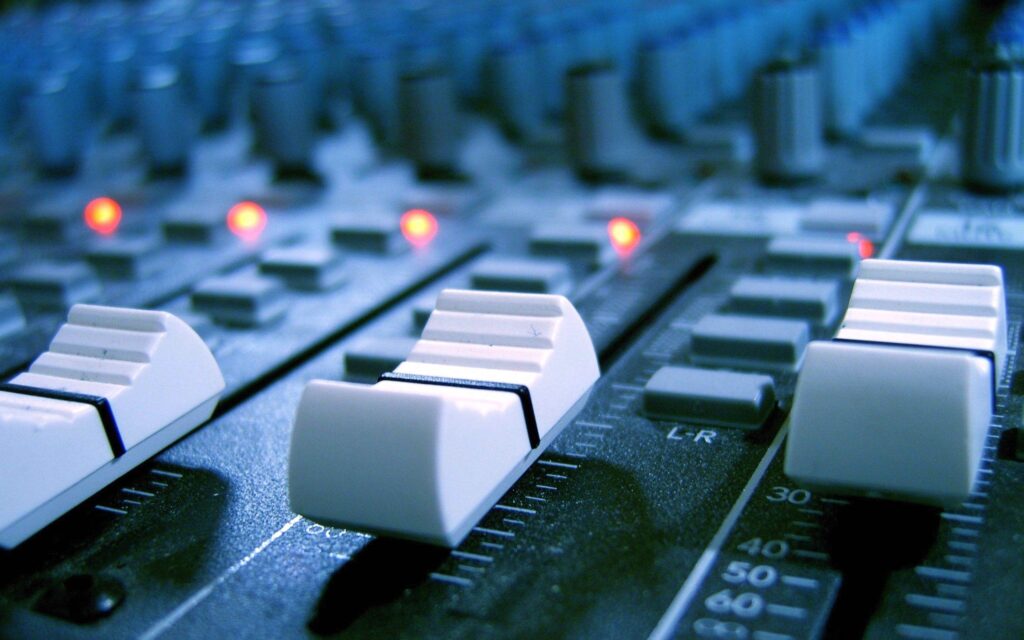 Music production studio with broadcast equipment, lighting and screens.